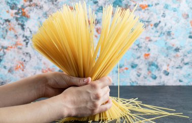 Kadın elleri arka planda spagetti tutuyor.