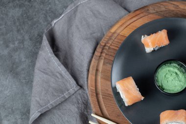 Tahta üzerinde wasabi sosuyla servis edilen somon suşisi ruloları.