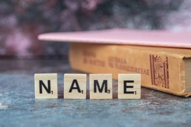 Tahta zarlarda siyah harflerle isim yazma ve eski bir kitap.