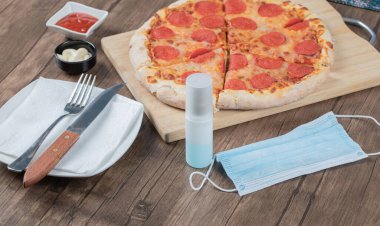 Biberli pizza ahşap bir tahtanın üzerinde sos, tabak, el dezenfektanı