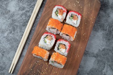 Suşi ahşap bir tahtanın üzerinde kırmızı havyarla yuvarlanıyor.