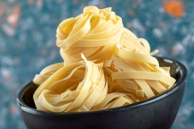 Renkli arka planda bir kase tagliatelle yuvası