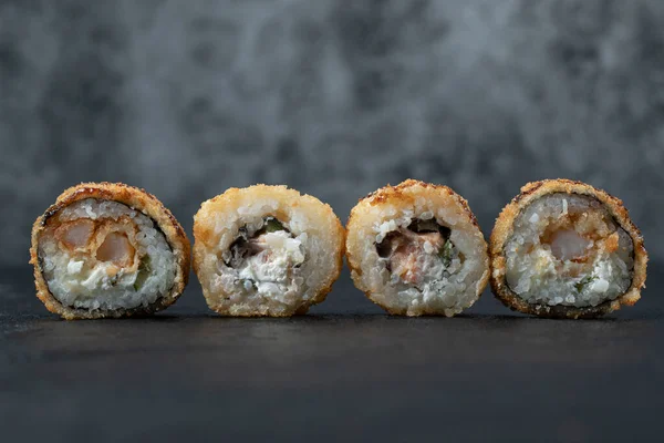 Mini sushi rullar med blandade ingredienser på svart bakgrund — Stockfoto