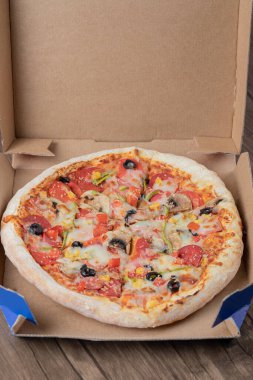 Karton paket servis kutusunda siyah zeytinli biberli pizza.