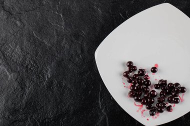 Siyah arka planda beyaz bir plakada kırmızı kuşüzümü ziyareti