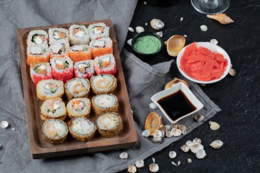 Suşi, soya sosu, zencefil ve wasabi ile ahşap bir tabakta.