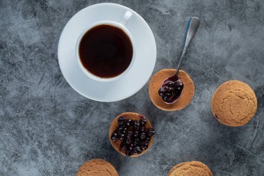 Bir fincan çayla servis edilen kuşüzümlü yulaflı kurabiyeler.