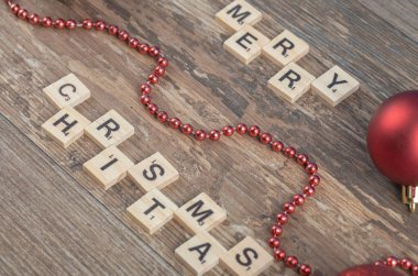 Ahşap bir güvertede, kırmızı toplar ve incilerle mutlu noeller.