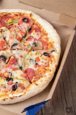 Karton paket servis kutusunda siyah zeytinli biberli pizza.