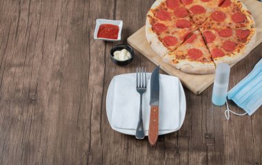 Biberli pizza ahşap bir tahtanın üzerinde sos, tabak, el dezenfektanı