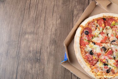 Karton paket servis kutusunda siyah zeytinli biberli pizza.