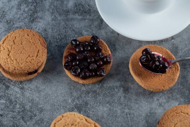 Bir fincan çayla servis edilen kuşüzümlü yulaflı kurabiyeler.