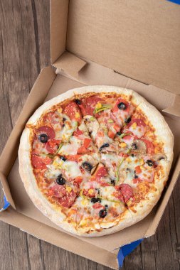 Karton paket servis kutusunda siyah zeytinli biberli pizza.