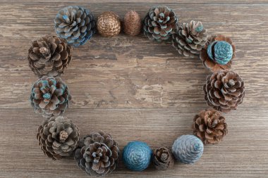 Ahşap güvertede doğal mavi ve altın renkli meşe ağacı konileri.