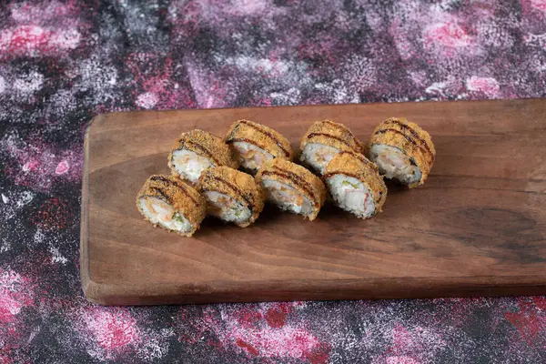 Rollos de sushi caliente con queso crema en una tabla de madera — Foto de Stock