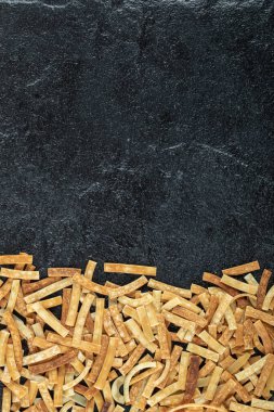 Koyu ahşap zemine saçılmış pişmemiş makarna.