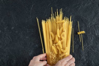 Kadın elleri çeşitli makarnalara dokunuyor.