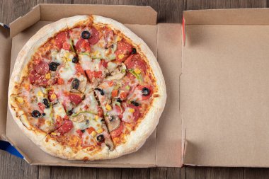 Karton paket servis kutusunda siyah zeytinli biberli pizza.