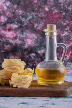 Çiğ tagliatelle yuvaları ve ahşap tahtada yağ