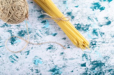 Mavi arka planda pişmemiş makarna ve iplik.