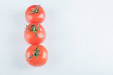 Beyaz arka planda üç tane taze domates.