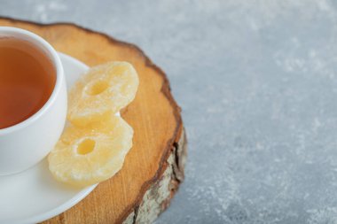 Koyu arkaplanda kurutulmuş ananas aromalı bir fincan çay.