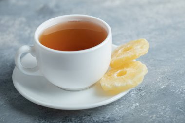 Koyu arkaplanda kurutulmuş ananas aromalı bir fincan çay.