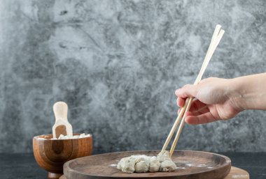 Çubuğu hamur köftesiyle tutarak.