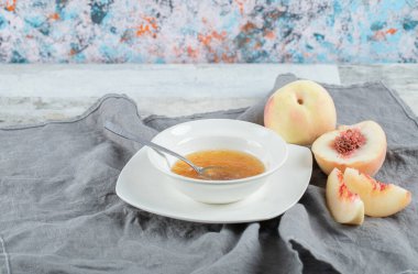 Şeftali reçeli ve kaşıkla dolu beyaz bir tabak