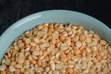 Koyu arkaplanda pişmemiş patlamış mısır olan mavi bir tabak.