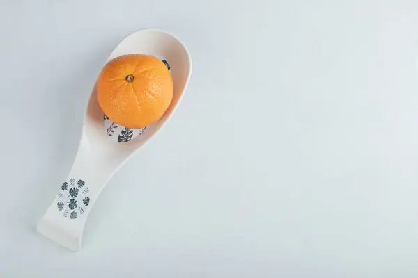 Una fruta naranja en una hermosa cuchara blanca — Foto de Stock