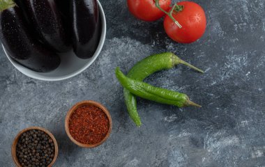 Çiğ patlıcan ve sebzeler ve gri arka planda baharatlar.