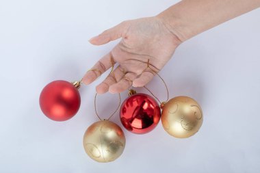 Beyaz arka planda pırıl pırıl Noel mücevherleri tutan bir kadın.