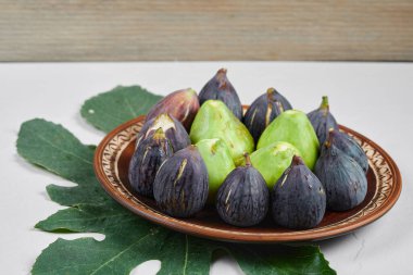 Seramik tabakta yeşil ve siyah incir yapraklı.