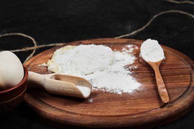 Tahtada un ve yumurta, siyah arka planda kaşıklar.