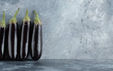 Gri arka planda olgun organik mor patlıcanlar