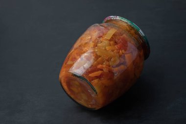 Siyah arka planda karışık sebzeli cam bir kavanoz.