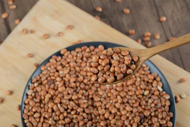 Tahta bir masada çiğ kahverengi fasulyeli koyu bir tabak.