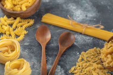 Ahşap kaşıklı çeşitli pişmemiş makarna çeşitleri.