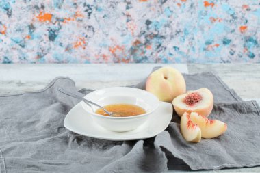 Gri masa örtüsü üzerinde reçelli ve şeftalili beyaz bir tabak