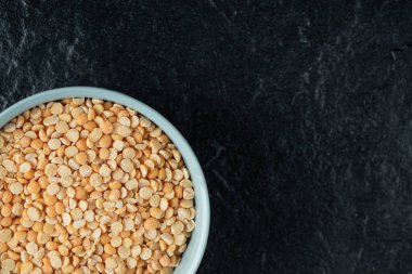 Arkaplanda hazırlıksız mercimek bulunan mavi bir tabak.