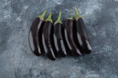 Gri arka planda taze patlıcan yığını