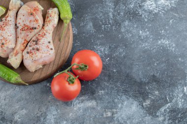 Çiğ baharatlı tavuk budu, yeşil biber ve domatesli yakın plan fotoğrafı.