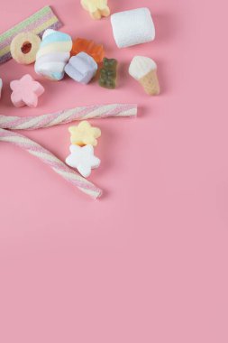 Pembe arka planda karışık şekerlemeler.