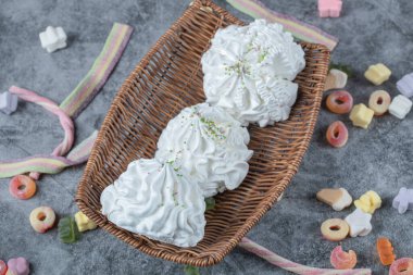 Etrafında renkli jelibonlar olan ahşap bir tabakta beyaz kremalı kurabiyeler. Yüksek kalite fotoğraf