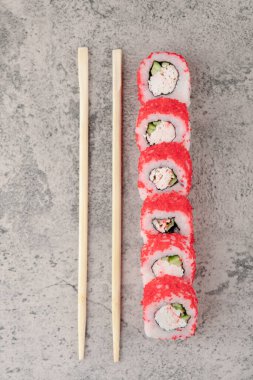 Kırmızı havyarlı suşi ve mermer arka planda yemek çubukları.