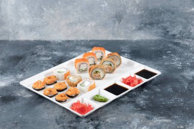 Beyaz tabak çeşitli lezzetli suşi mermer zemin üzerinde rulo