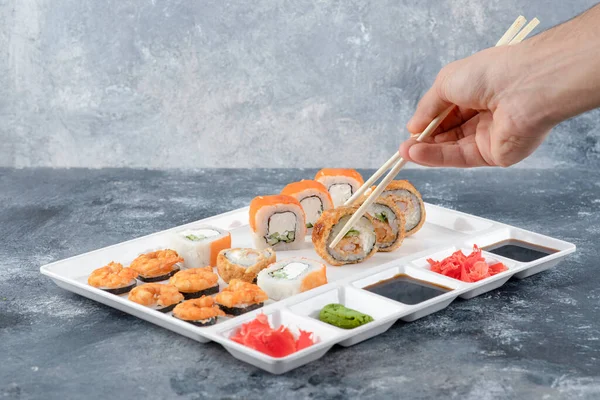 Man hand tar panerad varm sushi rulle med ätpinnen — Stockfoto