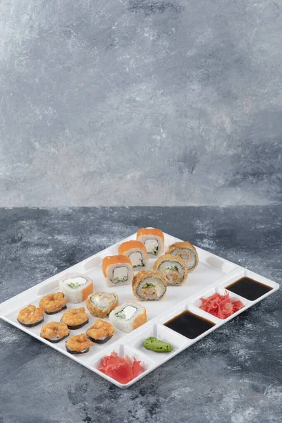 Vit platta av olika läckra sushi rullar på marmor bakgrund — Stockfoto