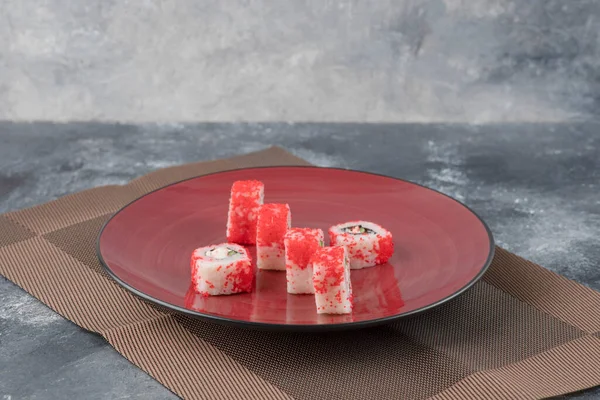 Βουργουνδία πιάτο ρολά σούσι με κόκκινο χαβιάρι σε μαρμάρινο φόντο — Φωτογραφία Αρχείου